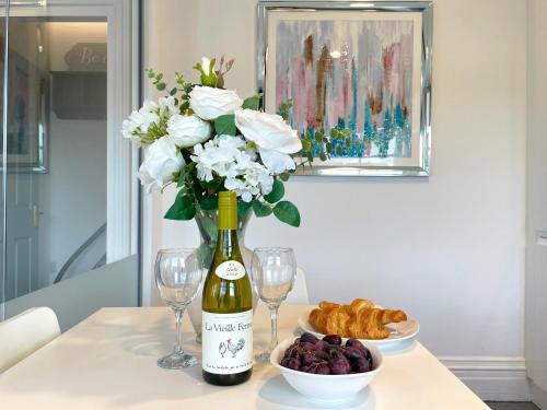 a bottle of wine and glasses and a vase of flowers at Elegant apartment in city center by HNFC Stays in Newcastle upon Tyne