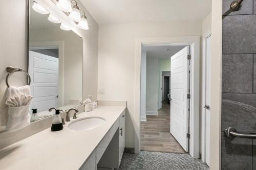 a white bathroom with a sink and a mirror at The Big Easy's Finest: 4-BR Luxury Condo in NOLA in New Orleans