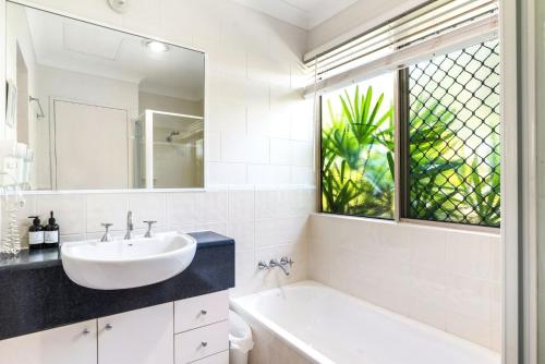 uma casa de banho com um lavatório, uma banheira e uma janela em Stay at the Albatross em Kewarra Beach