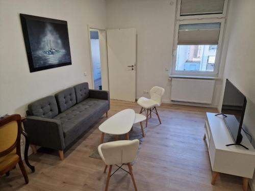 Apartments bei Marienplatz في شتوتغارت: غرفة معيشة مع أريكة وكراسي