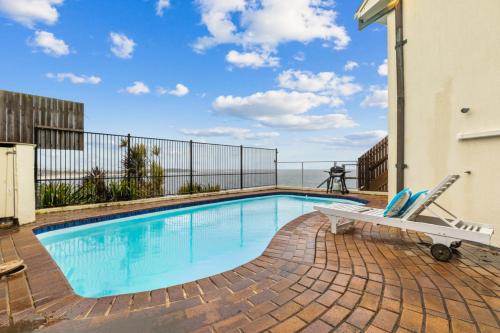 a swimming pool with a bench next to a building at Magical views of dee why in Deewhy