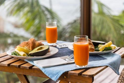 a table with two plates of food and two glasses of orange juice at Magical views of dee why in Deewhy
