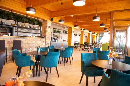 un restaurante con mesas y sillas azules y un bar en Hotel Rozálka en Pezinok