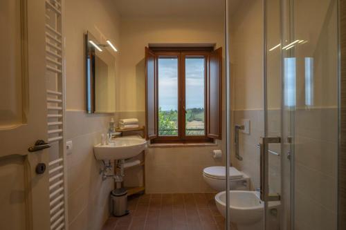 a bathroom with a sink and a toilet and a window at Affittacamere Podere Valserena in Monteroni dʼArbia