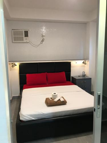 een bed met rode kussens en een dienblad met een kopje erop bij Logan Apartments in Bantayan