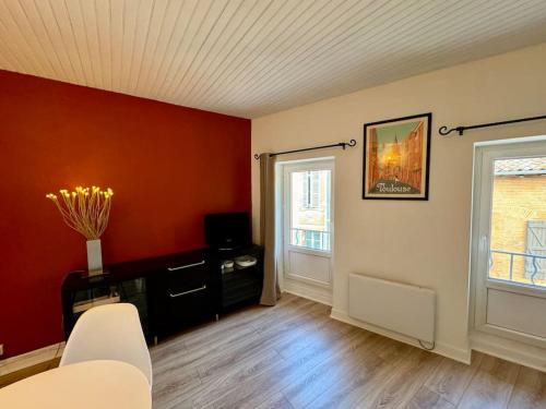 - un salon avec des murs rouges et une chaise blanche dans l'établissement Cœur Historique Studio de Charme, à Toulouse