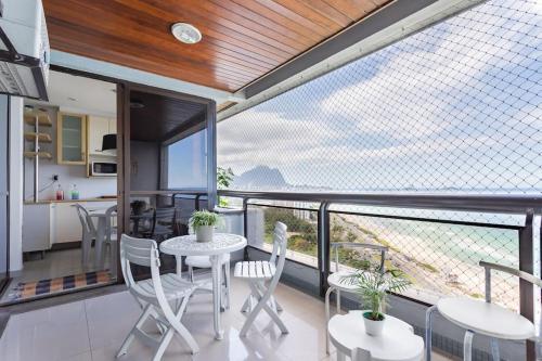 Habitación con balcón con mesa y sillas. en Vista DE CINEMA do 19 andar da Praia BARRA da TIJUCA - Portaria 24h, Estacionamento, Wi-Fi 35mbps, Ar Condicionado - BANHEIRO RECEM REFORMADO, en Río de Janeiro