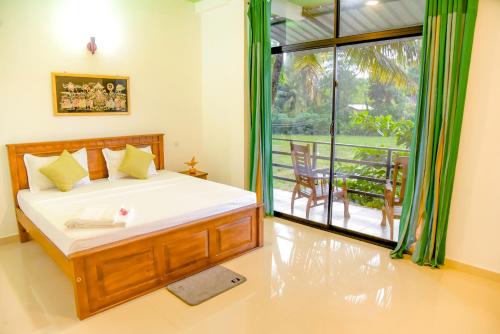 a bedroom with a bed and a view of a balcony at Paddy Field View Resort in Mirissa