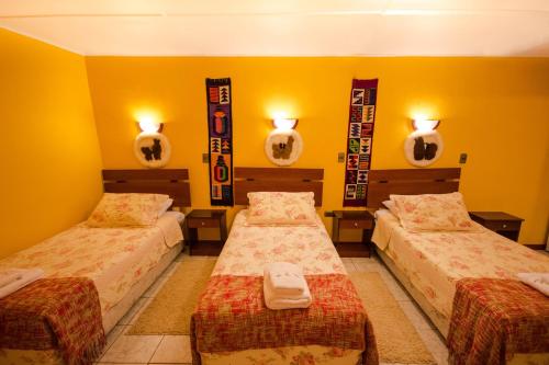 two beds in a room with yellow walls and mirrors at Hostal Kirckir in San Pedro de Atacama