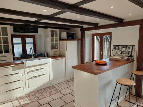 cocina con armarios blancos y techo de madera en Ferme des boudieres en Fresse-sur-Moselle