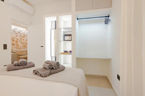 a white bedroom with two towels on a bed at Pithea Luxury Living in Koroni