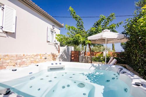 a hot tub in a yard with an umbrella at Pithea Luxury Living in Koroni