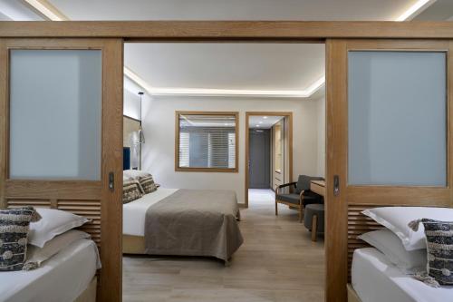 a bedroom with two beds and a desk at Atlantica Aegean Blue in Kolimbia
