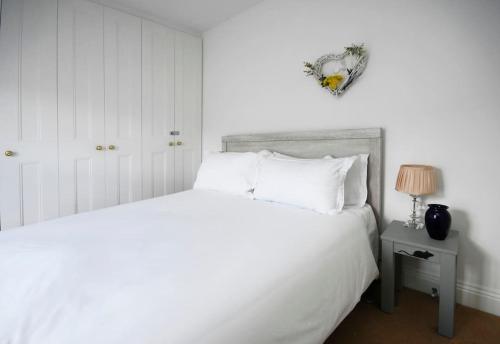 a bedroom with a white bed and a table with a lamp at Ivy Cottage in Henley on Thames