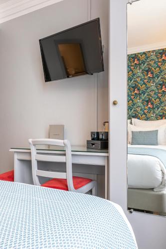 a bedroom with a desk with a tv on the wall at Splendid Hôtel in Paris