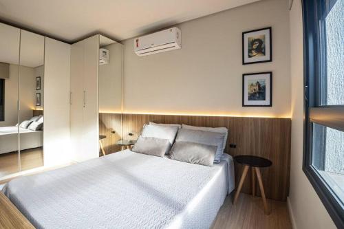 een slaapkamer met een groot wit bed en een raam bij Studio 309 Parque Una + garagem in Pelotas