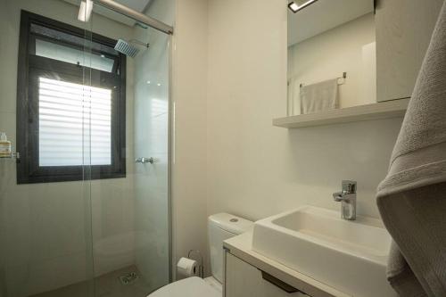een badkamer met een toilet, een wastafel en een douche bij Studio 309 Parque Una + garagem in Pelotas