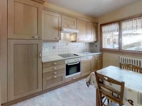 une cuisine avec des armoires en bois et un four à plaques de cuisson dans l'établissement Appartement cosy près des pistes avec balcon au Grand-Bornand - FR-1-467-56, au Grand-Bornand