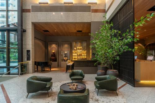 a lobby with green chairs and a piano at Laghetto Stilo São Paulo in Sao Paulo