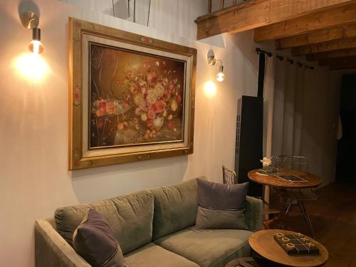 a living room with a couch and a painting on the wall at La Petite Grange - Spa Balnéo in Vigneux-de-Bretagne