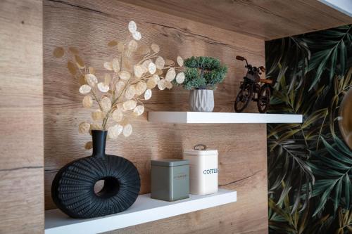 a black vase sitting on a white shelf at Happy Island Luxury Apartman Sárvár in Sárvár
