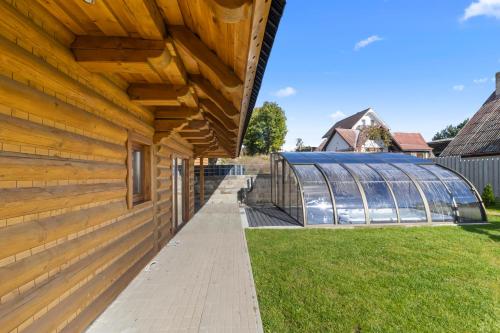 a wooden house with a glass greenhouse behind it at Chaty Kukana a Kuku in Vysoké Tatry