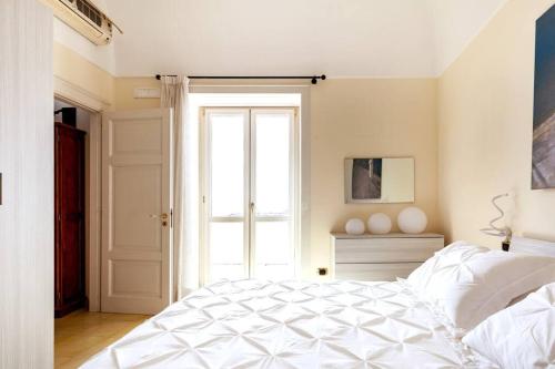 1 dormitorio con cama blanca y ventana en Casa del pozzo sulla spiaggia, en Cetara