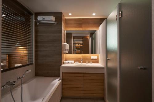 a bathroom with a tub and a sink and a mirror at Atlantica Aegean Blue in Kolimbia
