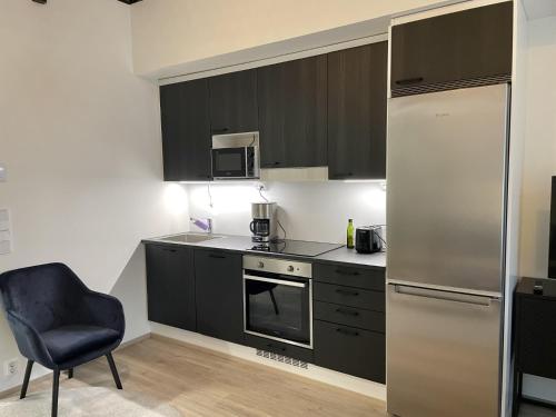 a kitchen with black cabinets and a chair and a refrigerator at Bright loft apartment with glazed balcony in Tampere