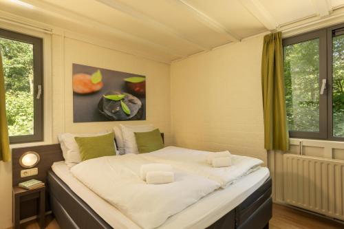 a large bed in a room with two windows at Center Parcs Limburgse Peel Limburg-Brabant in America