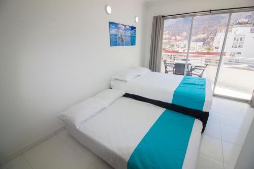 - une chambre avec 2 lits et une grande fenêtre dans l'établissement cristal caribe 309A, à Santa Marta