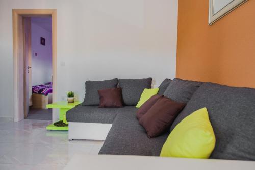 a living room with a gray couch with colorful pillows at Apartments Villa Monique in Rogoznica