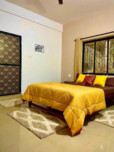 a bedroom with a bed with a yellow comforter and a window at Mitra Homes Mandrem in Mandrem