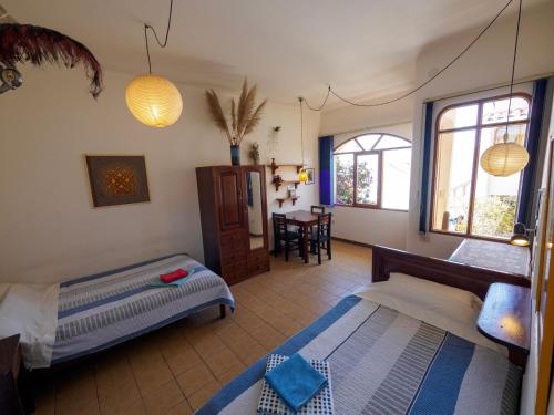 a bedroom with two beds and a table and windows at Bella Vista El Tronco in Sucre