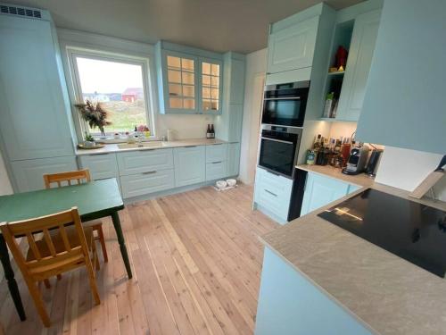 a kitchen with blue cabinets and a table and a counter at Idyllic and peaceful Family Home in Tromsø