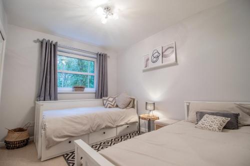 Un dormitorio con dos camas y una ventana. en Garden View Nook-2 bed apartment, en High Blantyre