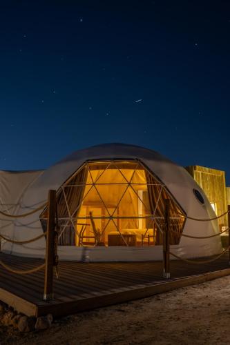 a dome tent is lit up at night at Pura Eco Retreat, Jebel Hafit Desert Park in Al Ain