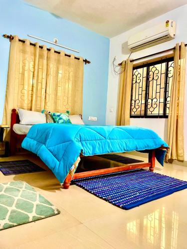 a bedroom with a bed with a blue comforter at Mitra Homes Mandrem in Mandrem