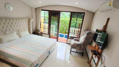 Schlafzimmer mit einem Bett, einem TV und einem Stuhl in der Unterkunft Venetian Signature Condo Resort Pattaya in Jomtien Beach