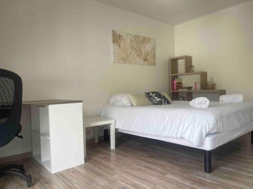 una camera con letto bianco e scrivania di T2 Saint Laurent a Orléans
