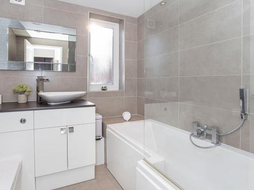 uma casa de banho com um lavatório, uma banheira e um espelho. em Holgate Lodge em York