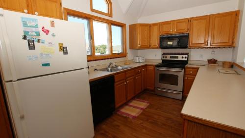 a kitchen with wooden cabinets and a white refrigerator at Oceanside, Private Pool, Community Pool, Sun Deck, SP8, Ole Duck Haven in Duck