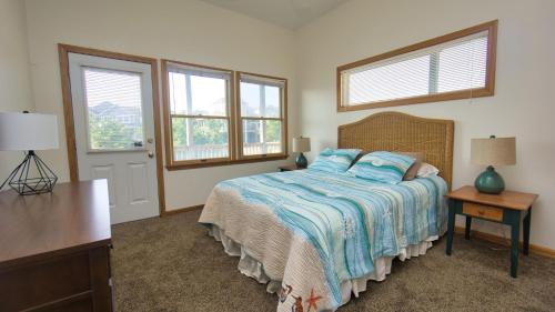 a bedroom with a bed with a blue comforter and two windows at Oceanside, Private Pool, Community Pool, Sun Deck, SP8, Ole Duck Haven in Duck