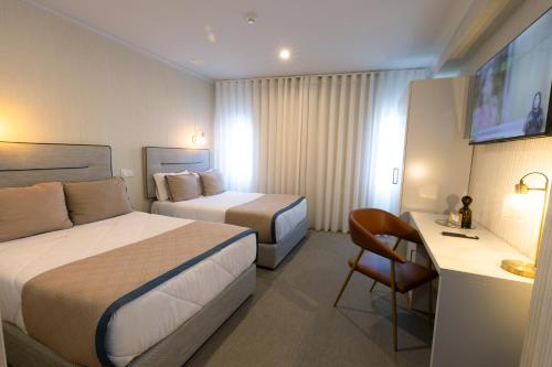 Una habitación de hotel con dos camas y un escritorio. en Hotel America, en Oporto