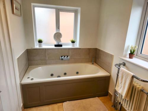a large bath tub in a bathroom with a window at Aldrich Villa, 5-Bed Luxury House, Oxford, Parking in Oxford