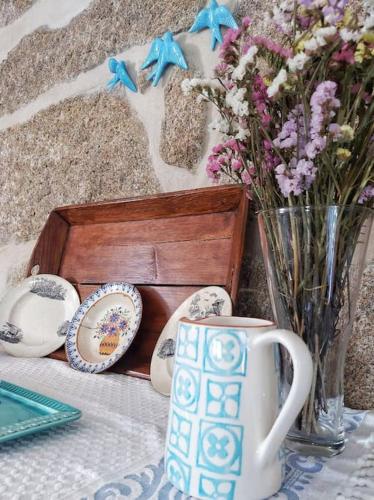 a table with a cup and a vase of flowers at A Casa do Soito in Oliveira do Hospital