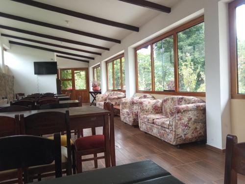 ein Wohnzimmer mit Sofas, einem Tisch und Fenstern in der Unterkunft Casa de Mama Valle - Urubamba in Urubamba