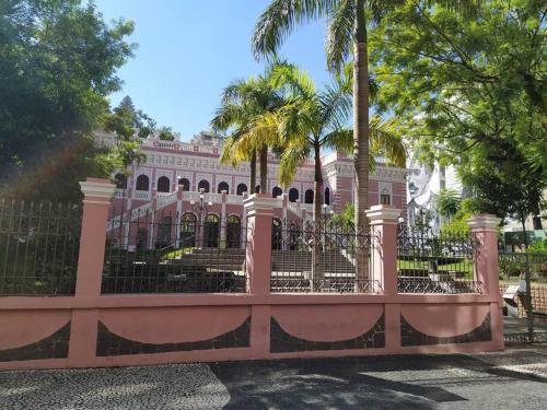 uma cerca rosa em frente a um edifício com palmeiras em Bebel 1108 em Florianópolis