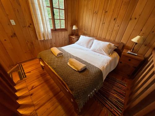 a bedroom with a bed with two towels on it at Green Baker Lodge in Puerto Bertrand