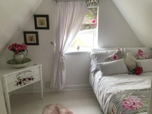 um quarto com uma cama e uma janela com flores em The Miners Cottage em Blackwood